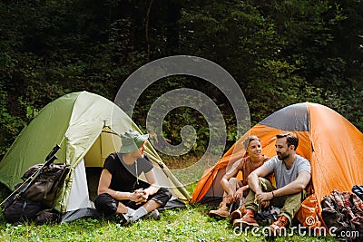 Young travelers resting in tents while hiking in green forest Stock Photo