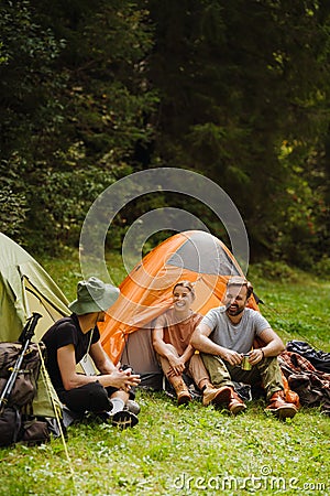 Young travelers resting in tents while hiking in green forest Stock Photo