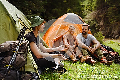 Young travelers resting in tents while hiking in green forest Stock Photo