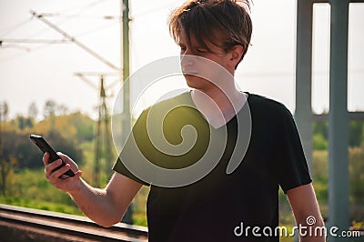 Young traveller man talking through the phone at the railway station during hot summer weather, making gestures while talking Stock Photo