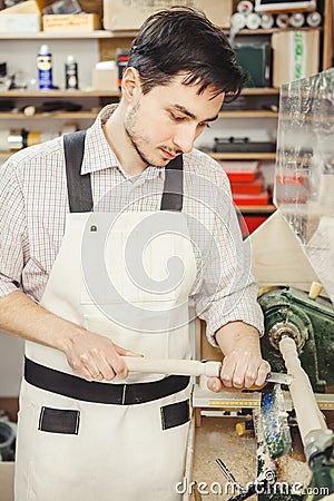 Young turner engages in wood carving on lathe for wood Stock Photo