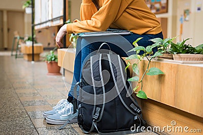 Young unrecognisable depressed lonely female college student sitting in the hallway at her school. Stock Photo