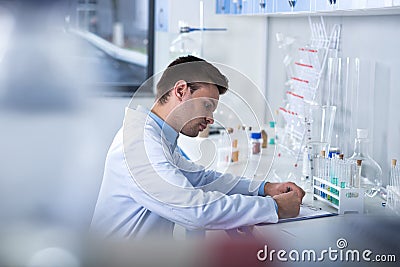 Young unshaken researcher sitting and working with his notebook. Stock Photo