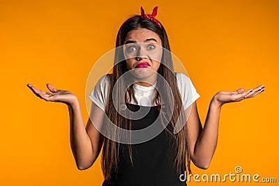 Young unsure girl shrugs her arms, makes gesture of I don`t know, care Stock Photo