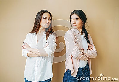 Young upset girls friends in casual offended at each other on the beige background Stock Photo