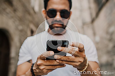 Young urban professional man using smart phone. Hipster coworker holding mobile smartphone using app texting sms message Stock Photo