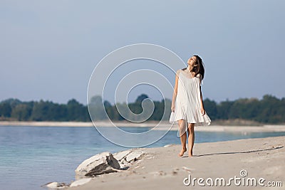 Young very beautiful girl with long hair in a white dress by the lake. Stock Photo