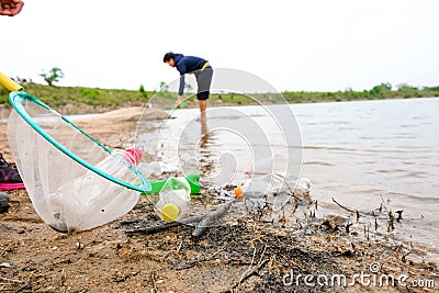 Young volunteers with garbage bags cleaning area in dirty beach of the lake, Volunteer concept. Stock Photo