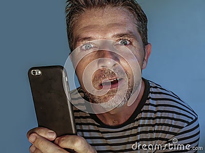 Young weird and crazy mobile phone addict man using cell compulsively with weird and freak face expression in internet social Stock Photo