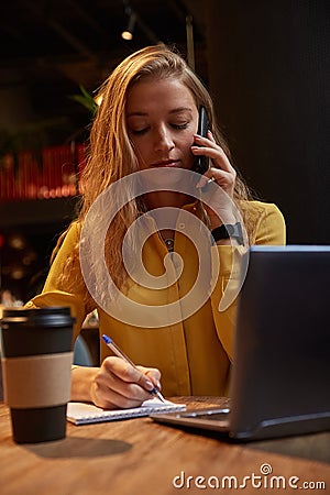 young well dressed cauasian woman sitting at coffee shop, calling by smartphone Stock Photo