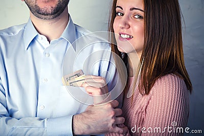 Young wife pulls out dollar bills from her husband`s shirt pocket, husband grabbed her hand and does not allow to pull Stock Photo