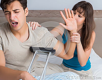 Young wife supporting husband on crutch after injury Stock Photo