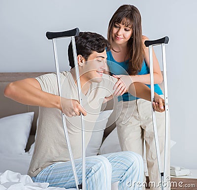 Young wife supporting husband on crutch after injury Stock Photo