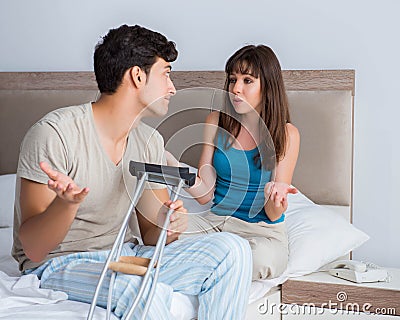 Young wife supporting husband on crutch after injury Stock Photo