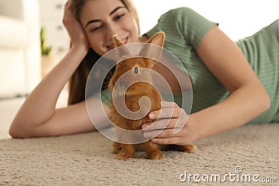 Young woman with adorable rabbit on floor. Lovely pet Stock Photo