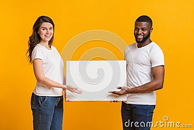 Young woman and afro man holding and pointing at blank placard Stock Photo
