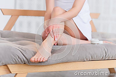 Young woman applying body cream on her legs with smooth soft skin indoors, closeup. Beauty and body care Stock Photo