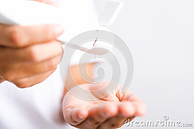 Young woman applying drop dispenser sanitizer alcohol gel on hand Stock Photo