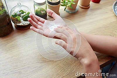 Young woman applying hands cream at wooden table. Stock Photo