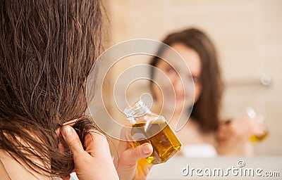 Young woman applying oil mask to hair tips Stock Photo