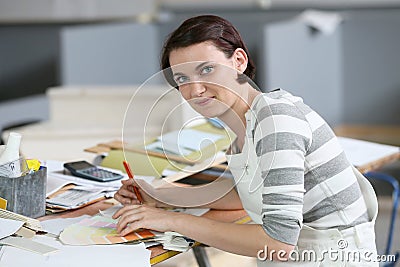 Young woman apprentice painter sitting at working table Stock Photo