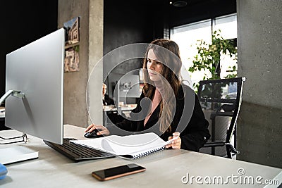 Young woman architect working with blueprints and technical design project at work table and computer in office Stock Photo