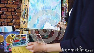 Young woman artist draw pictrure with watercolor paints and brush on easel canvas Stock Photo