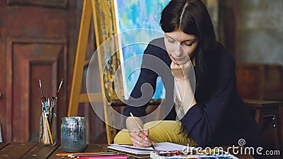 Young woman artist draw pictrure with watercolor paints and brush on easel canvas Stock Photo