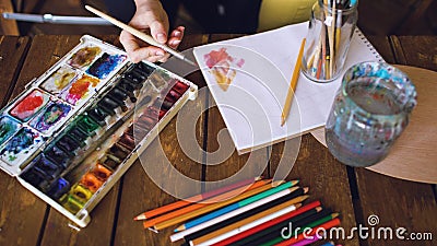 Young woman artist draw pictrure with watercolor paints and brush mixing colors closeup Stock Photo