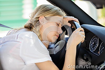 young woman asleep slumped over wheel car Stock Photo