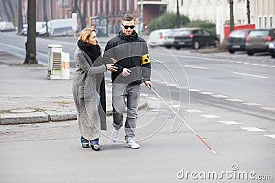 Woman Assisting Blind Man On Street Stock Photo