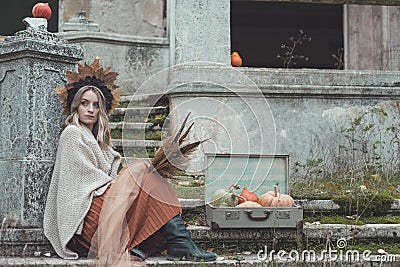 Young woman in autumn styled clothes sitting on rustic stairs Stock Photo