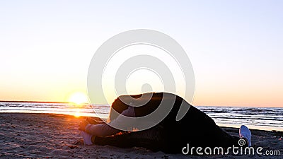 A young woman on the background of the sunset the sun on the seashore does exercises exercised by running, stretching and slumping Stock Photo