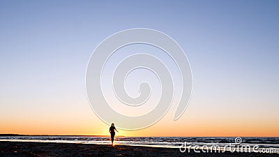 A young woman on the background of the sunset the sun on the seashore does exercises exercised by running, stretching and slumping Stock Photo