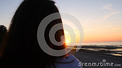 A young woman on the background of the sunset the sun on the seashore does exercises exercised by running, stretching and slumping Stock Photo