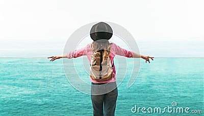 Young woman backpacker exploring new destinations - Back view of travel girl looking the ocean horizon Stock Photo