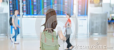 Young woman with bag and luggage looking to flight time information board in international airport, before check in. Travel, Stock Photo