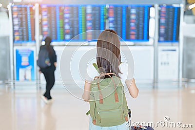 Young woman with bag and luggage looking to flight time information board in international airport, before check in. Travel, Stock Photo