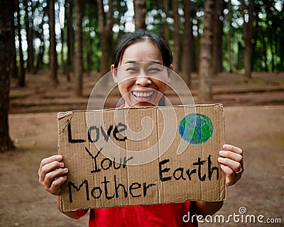 The young woman with banners protesting over pollution and global warming in the forest to save planet earth. The concept of World Stock Photo