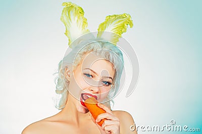 Young woman with banny ears eat carrot. Cute bunny rabbit. Easter bunny dress. Stock Photo