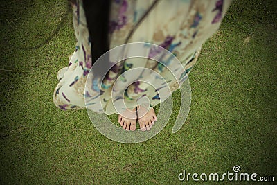 Young woman barefoot walking on the fresh, green grass in sunny summer in the morning. Restful moment. Healthy lifestyle. Brigh Stock Photo