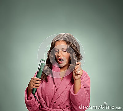 Young woman in bathrobe holding hair iron Stock Photo