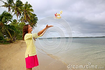 Young woman on a beach throwing flowers in the air Stock Photo