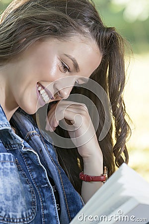 Young woman with a beautiful face carefully reads the book Stock Photo