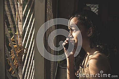 A young woman begins to cry and be overcome with emotions while realizing the bad news told to her via the phone Stock Photo