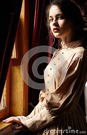 Young woman in beige vintage dress of early 20th century standin Stock Photo