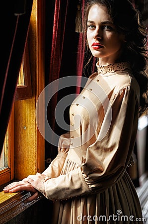 Young woman in beige vintage dress of early 20th century standin Stock Photo