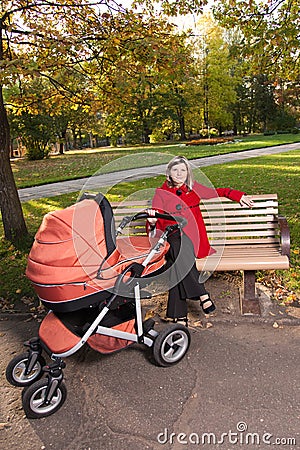 Young woman on bench with a pram. Stock Photo