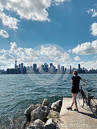 Young woman with bicycle enjoying cityscape view on Toronto city in Canada. Sport summer activity in modern large town. Canadian Stock Photo