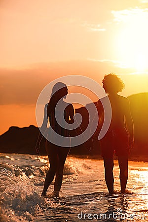 Young woman in bikini and her on beach at sunset. Lovely couple Stock Photo